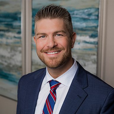david-stryzewski Professional man with short hair and a beard wearing a suit and tie, smiling against a backdrop of abstract art.