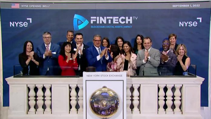 Vince Molinari and Mitch Chait with the FINTECH.TV team on the NYSE stage, blue branded backdrop, diverse group in business attire, celebratory clapping