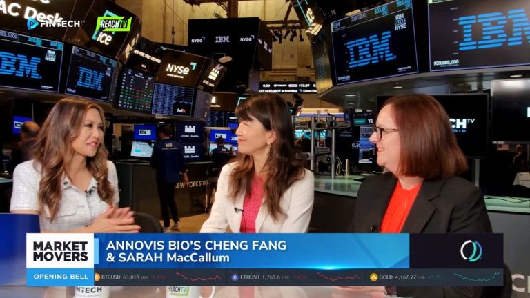 Three women talk on the NYSE trading floor beneath IBM screens, with a Market Movers lower third naming Annovis Bio's Cheng Fang and Sarah MacCallum.